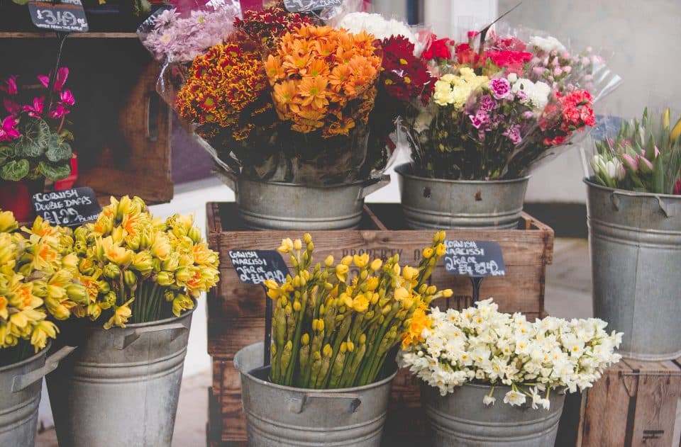 L'étal d'un fleuriste de quartier, seaux de fleurs coupées posés sur des cagettes